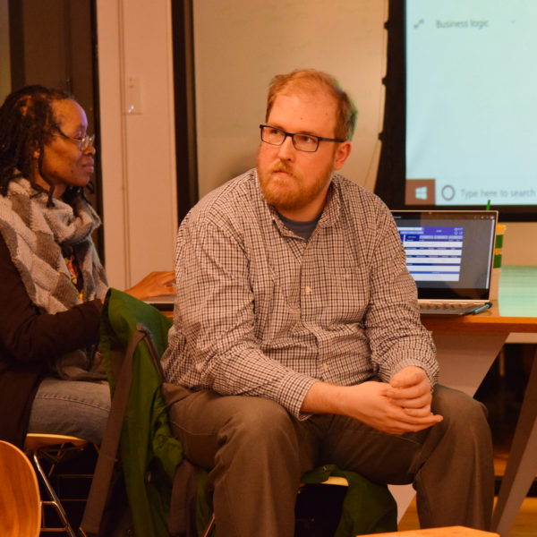 Two people sitting down and listening to the presentation