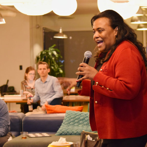 A presenter speaking to a room of people using a microphone