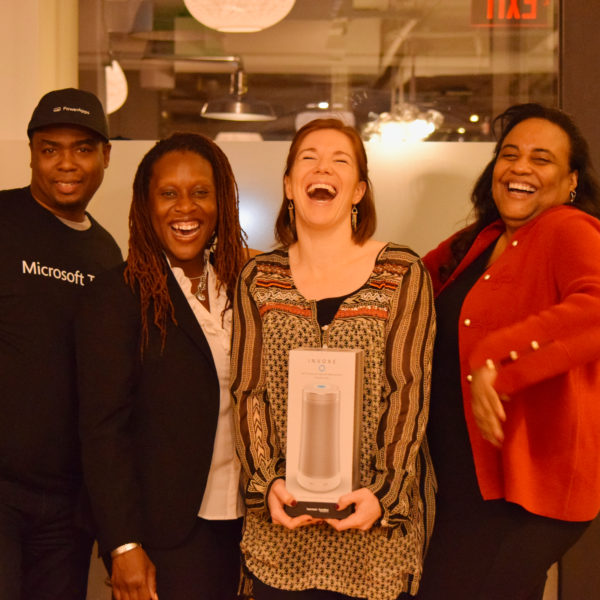 Four presenters smiling in a photo after gifting one of them with a portable speaker