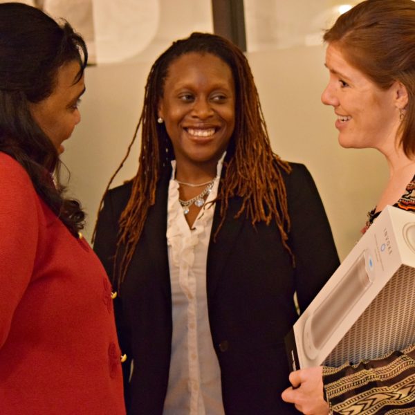 Two presenters speaking to another presenter while smiling